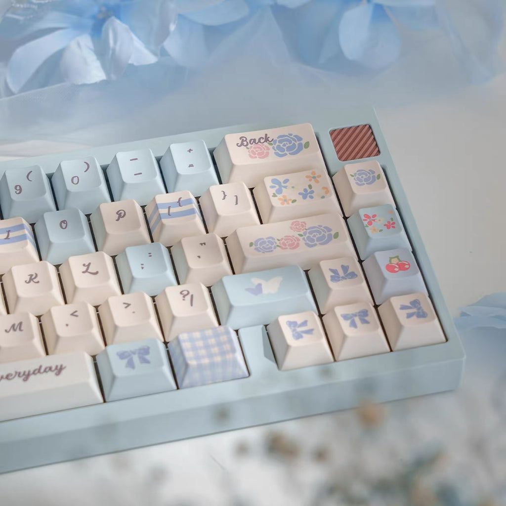 Keyboard keycaps with decorative patterns on a light blue base