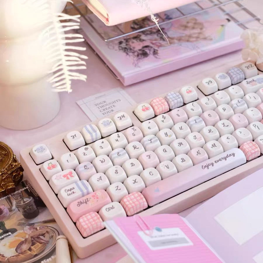 Keyboard with decorative keys on a desk with pink accessories