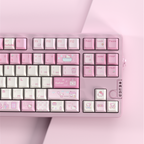 A close-up of a pastel pink mechanical keyboard with decorative keycaps featuring Hello Kitty illustrations, set against a matching pink background.