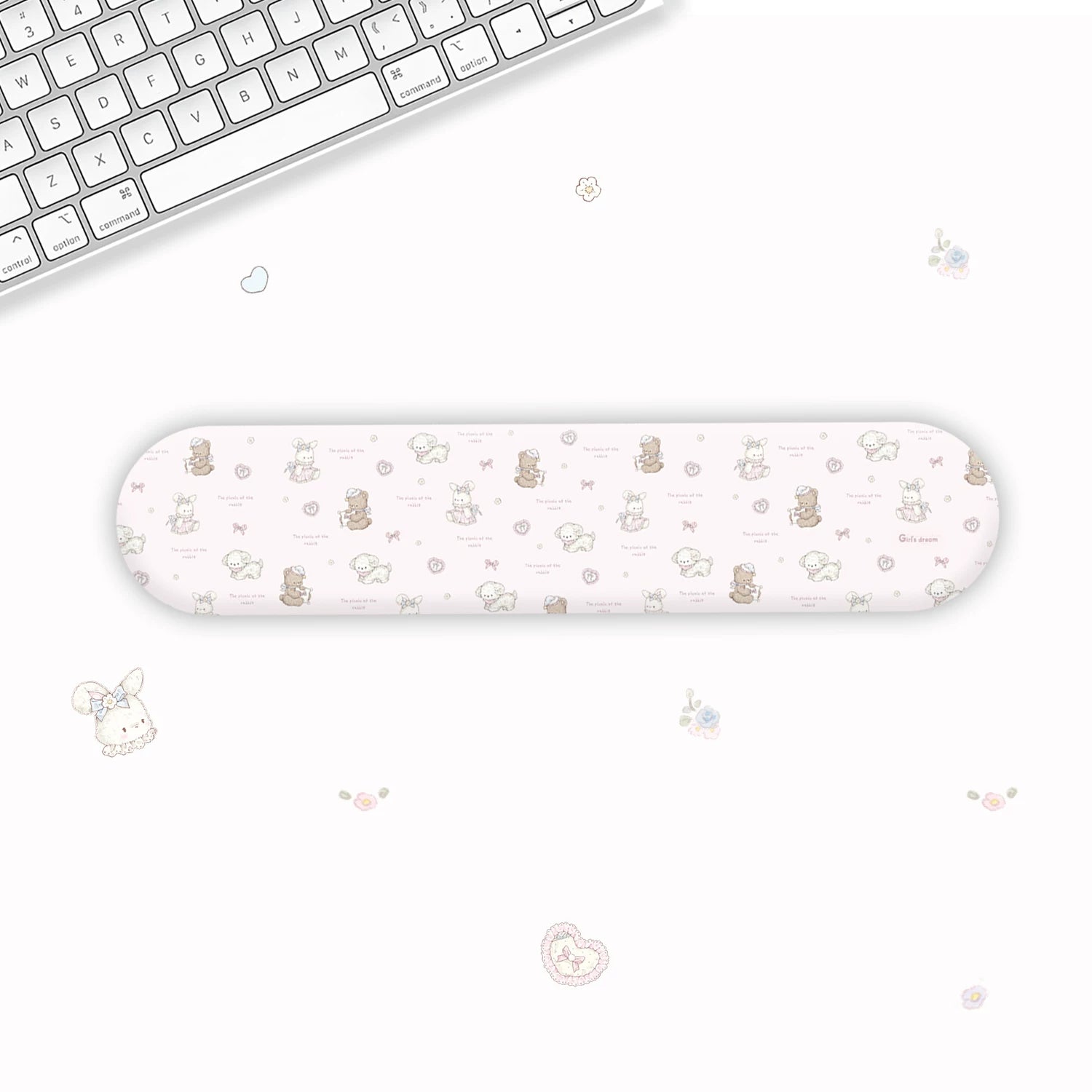 A long, narrow wrist rest with a cute pastel cartoon pattern of bears, hearts, and flowers, displayed on a clean white desk next to a keyboard.