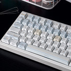 Close-up of a mechanical keyboard with gray and white keys on a dark surface.