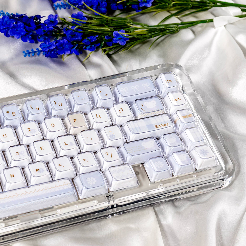 White keyboard on a white surface with blue flowers in the background