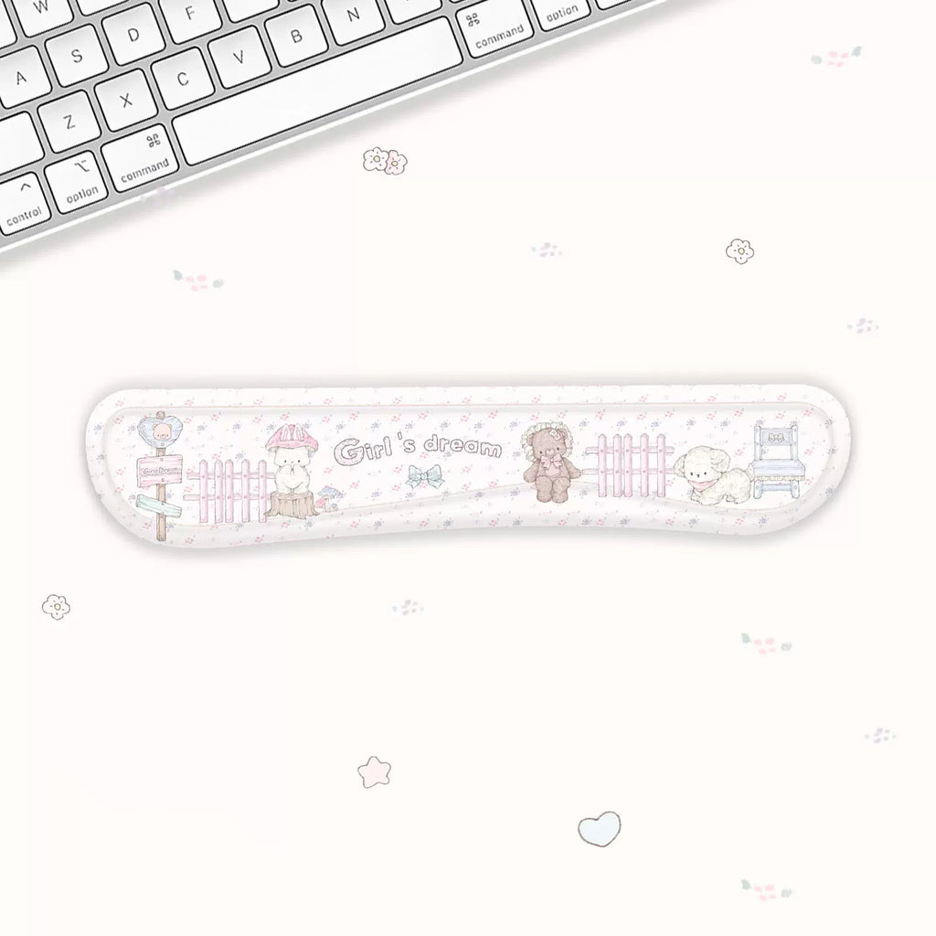 A long, narrow desk mat with a cute pastel cartoon design, placed on a white desk next to a keyboard. The desk mat features illustrations of a bunny, bear, sheep, and a fence, with the text 'Cute's dream' in the center.