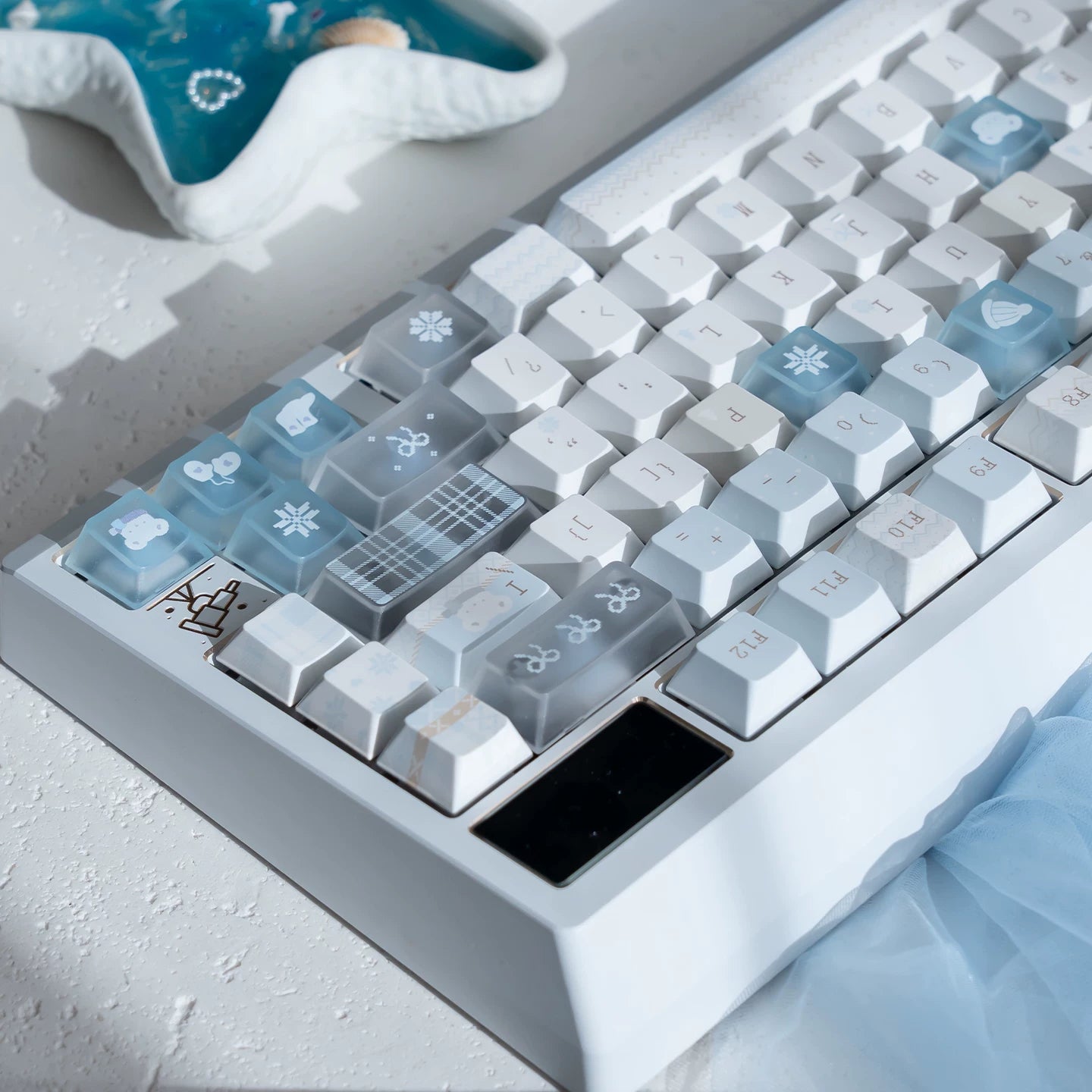 Close-up of a mechanical keyboard with decorative keycaps on a light gray surface.