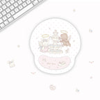 A round gel mouse pad with a pastel illustration of a fountain and two angel characters, shown on a white desk next to a keyboard. The pad has a pink wrist rest and the text 'Sweet dream' on it.