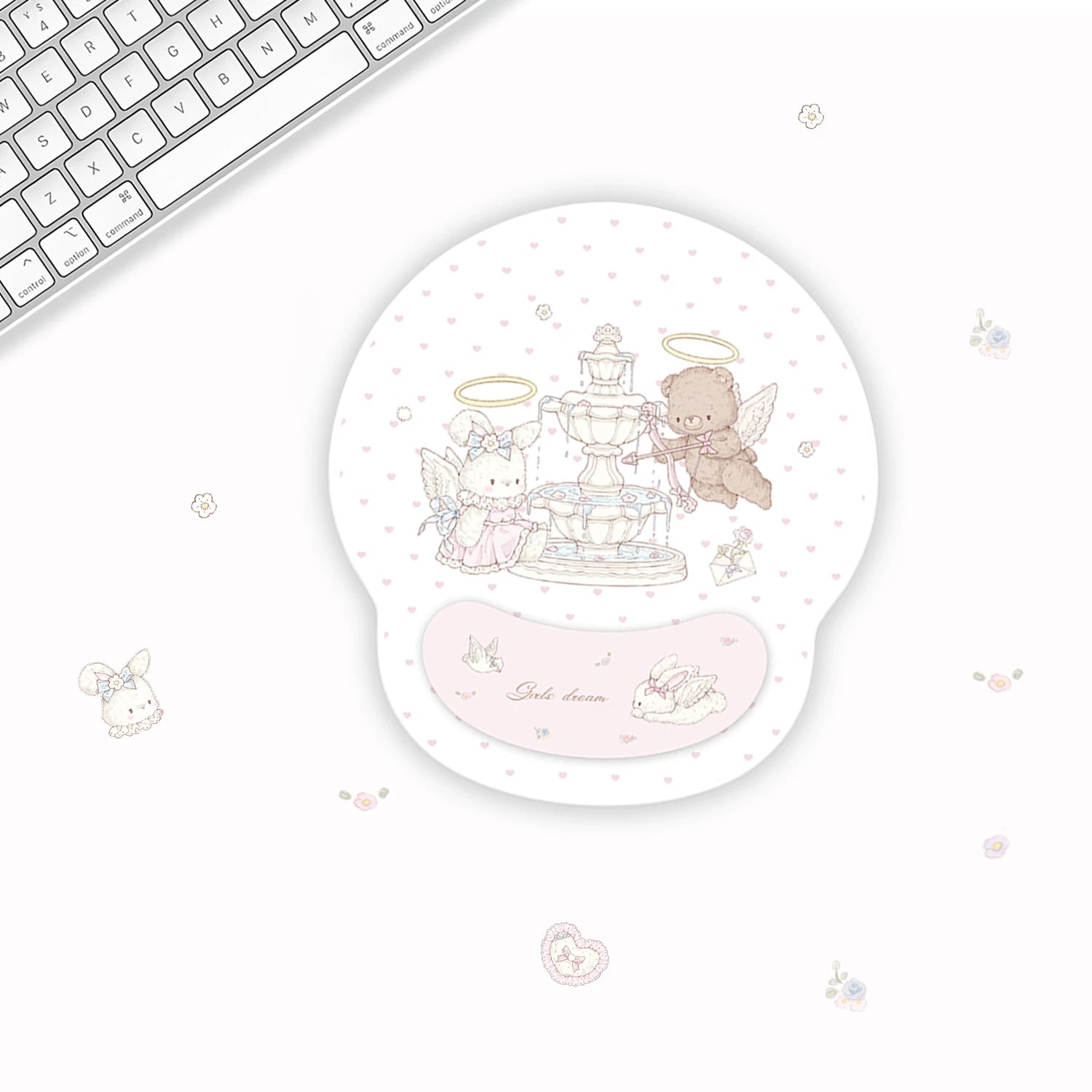 A round gel mouse pad with a pastel illustration of a fountain and two angel characters, shown on a white desk next to a keyboard. The pad has a pink wrist rest and the text 'Sweet dream' on it.